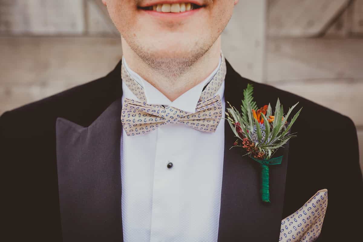 A groom with a large textured buttonhole pinned to his suit