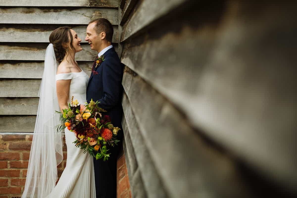 A bride and groom: the bride is holding a large bouquet with many different types of flowers